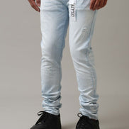 Person wearing light blue jeans with a brand logo on a gray background
