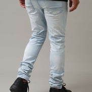 Person wearing light blue jeans and black shoes on a plain background