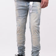 Person wearing light blue jeans with branding on a white background