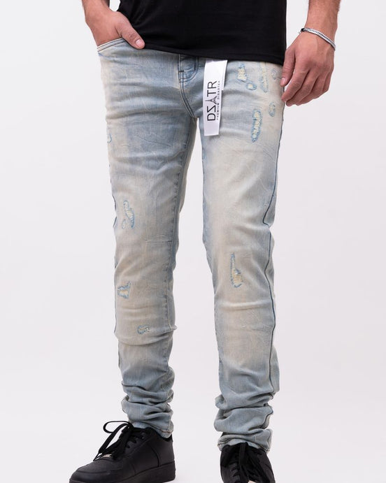 Person wearing light blue jeans with branding on a white background
