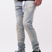 Person wearing light blue distressed jeans with a brand logo on a white background