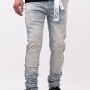 Person wearing light blue distressed jeans with a brand label on a white background