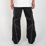 Black wide-leg pants with white geometric piping details, shown on a model from the back wearing a white t-shirt and white sneakers against a light gray background.