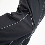 Close-up of a black athletic jacket sleeve with contrasting light gray piping, shown against a plain white background.