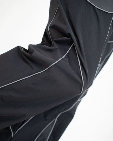 Close-up of a black athletic jacket sleeve with contrasting light gray piping, shown against a plain white background.