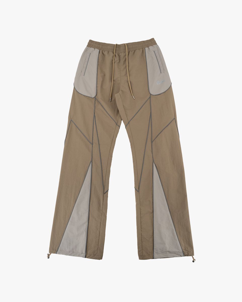 A pair of wide-leg pants in a taupe-beige color with contrasting light gray geometric paneling and a drawstring waist, shown against a plain light gray background.