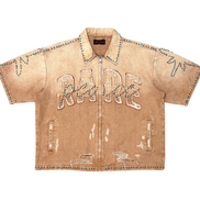 Beige denim shirt with 'RADE' embroidery on a white background