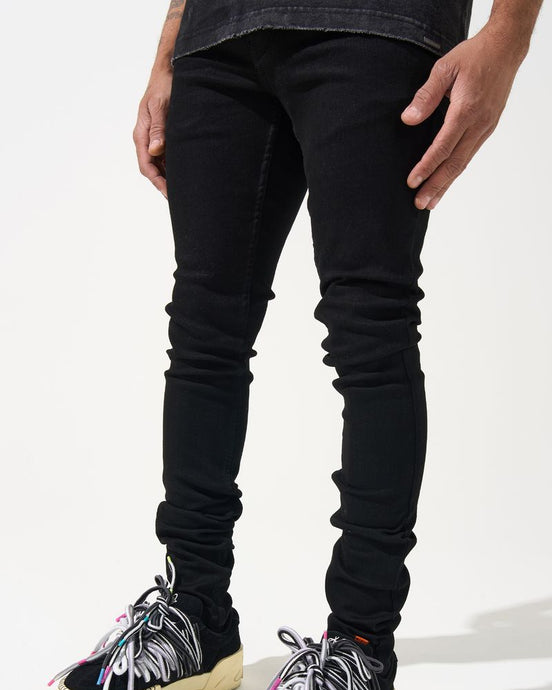 Person wearing black jeans and colorful sneakers on a white background