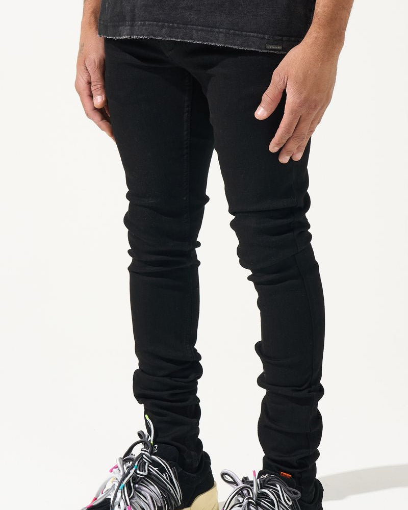 Person wearing black jeans and colorful sneakers on a white background