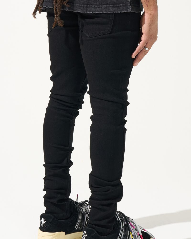 Person wearing black jeans and colorful sneakers on a white background