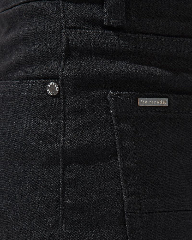 Close-up of black pants with a brand label on the pocket.