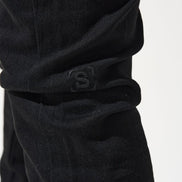 Close-up of black pants with a logo on a white background
