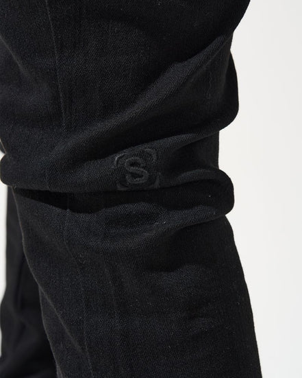Close-up of black pants with a logo on a white background