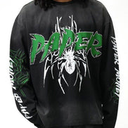A person wearing a black long-sleeve graphic sweatshirt with a large green and white 'PAPER' spider design on the front, plus green and white text down both sleeves, against a plain white background.