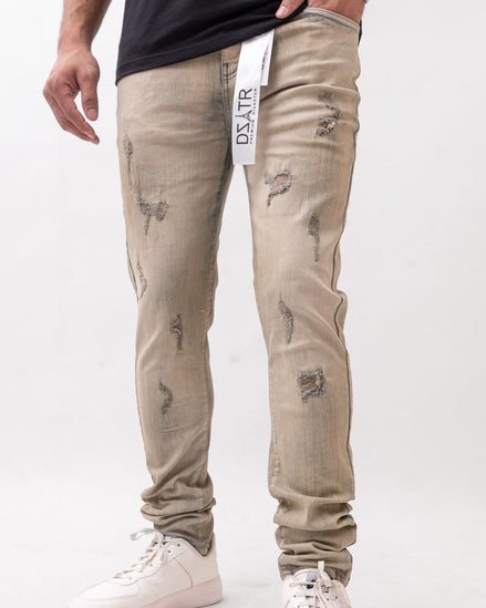 Beige distressed jeans worn by a person on a white background