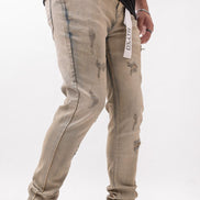 Person wearing beige distressed jeans with a white background