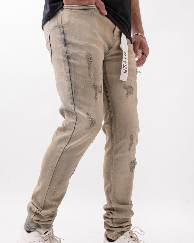 Person wearing beige distressed jeans with a white background