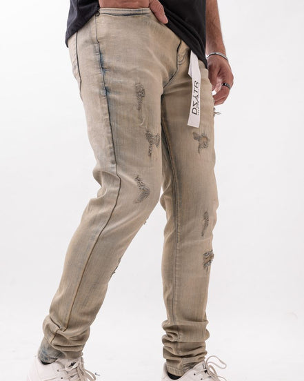 Person wearing beige distressed jeans with a white background