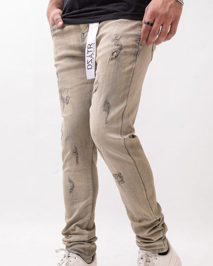 Beige distressed jeans worn by a person on a white background