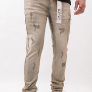 Beige distressed jeans with a brand label worn by a person on a white background