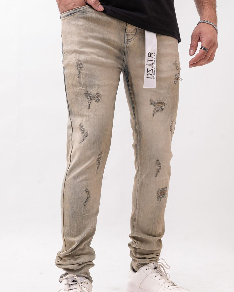 Beige distressed jeans with a brand label worn by a person on a white background