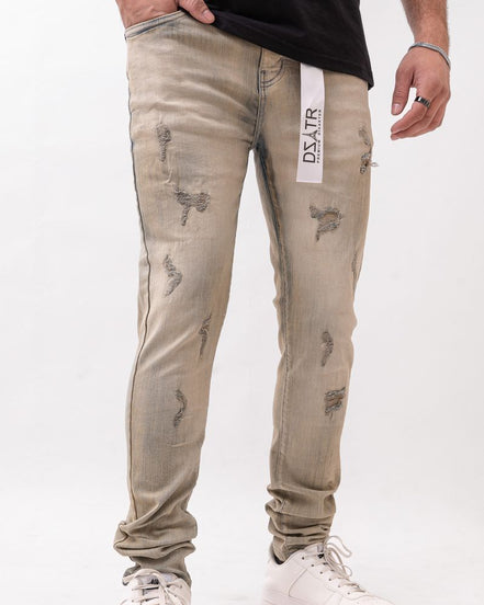Beige distressed jeans with a brand label worn by a person on a white background