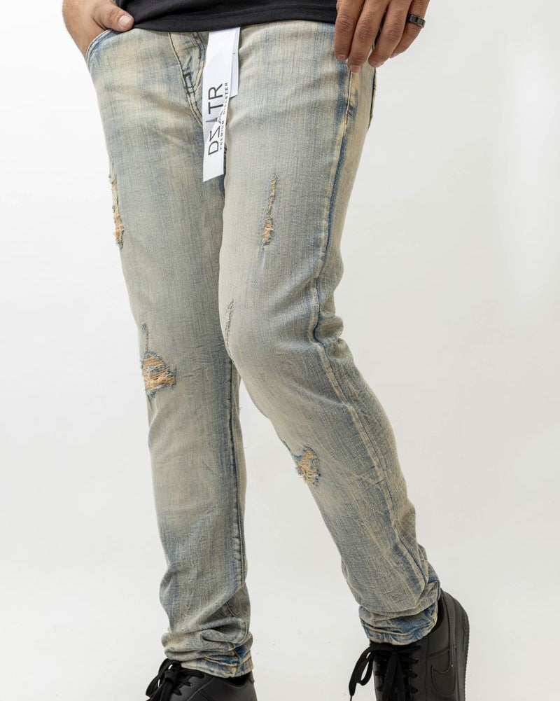 Person wearing distressed light blue jeans with a visible brand label on a white background