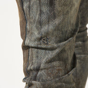 Close-up of a person wearing gray jeans with a visible brand logo on a white background