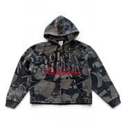 A cropped zip-up hoodie featuring a dark gray and black camouflage pattern with distressed details, a large 'Voices From The Streets' graphic on the chest, and ribbed cuffs and hem, shown flat on a white background.