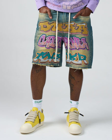 Person wearing colorful shorts with graffiti-style text and yellow sneakers on a white background