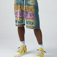 Person wearing denim shorts with colorful graphics and yellow sneakers on a white background