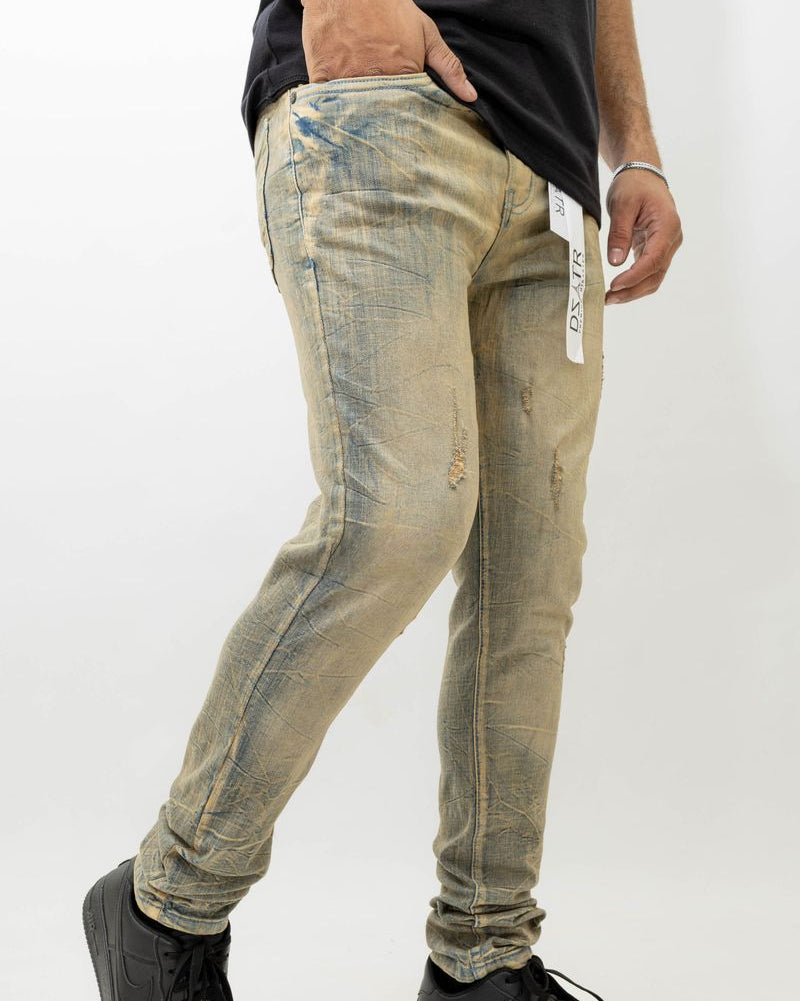 Person wearing distressed beige jeans with a white background