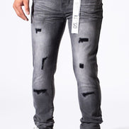 A person wearing slim-fit gray distressed jeans with ripped details and white sneakers, shown from the waist down against a plain white background.