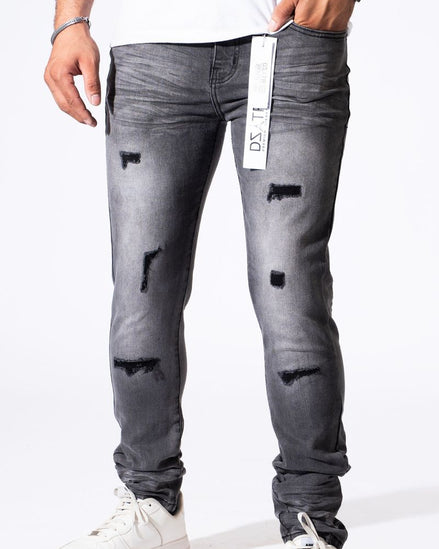 A person wearing slim-fit gray distressed jeans with ripped details and white sneakers, shown from the waist down against a plain white background.
