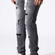 A person wearing distressed gray slim-fit jeans with ripped details and white sneakers, shown from the waist down against a plain white studio background.