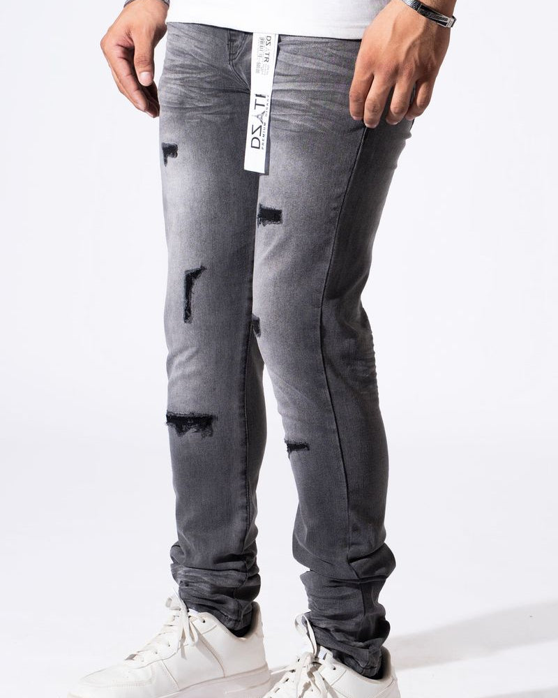 A person wearing distressed gray slim-fit jeans with ripped details and white sneakers, shown from the waist down against a plain white studio background.