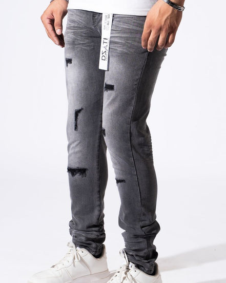 A person wearing distressed gray slim-fit jeans with ripped details and white sneakers, shown from the waist down against a plain white studio background.
