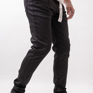 Person wearing black pants with a visible brand label on a white background