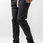 Person wearing black pants with a brand logo and white sneakers on a light gray background