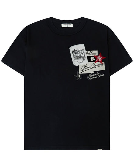 A black short-sleeve crewneck t-shirt featuring a graphic collage print on the left chest with white, red, and black elements, displayed against a solid white background.