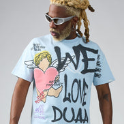 Person wearing a light blue t-shirt with graphic designs and text, standing against a plain background.