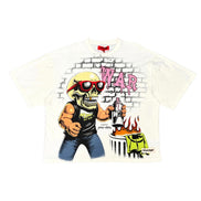 A white short-sleeve graphic t-shirt featuring a cartoon illustration of a skull in a yellow helmet and red sunglasses, holding a gun next to a burning car, with the word 'WAR' in pink graffiti-style letters on a brick wall background.