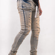 Person wearing distressed light blue jeans and white sneakers on a plain background