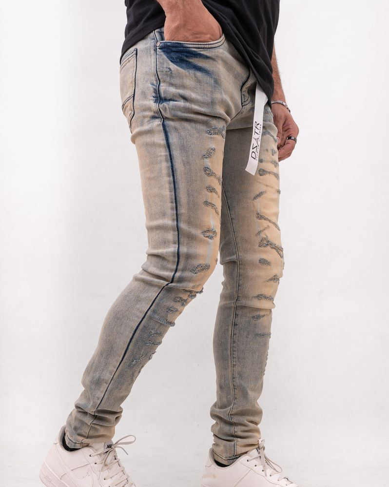 Person wearing distressed light blue jeans and white sneakers on a plain background