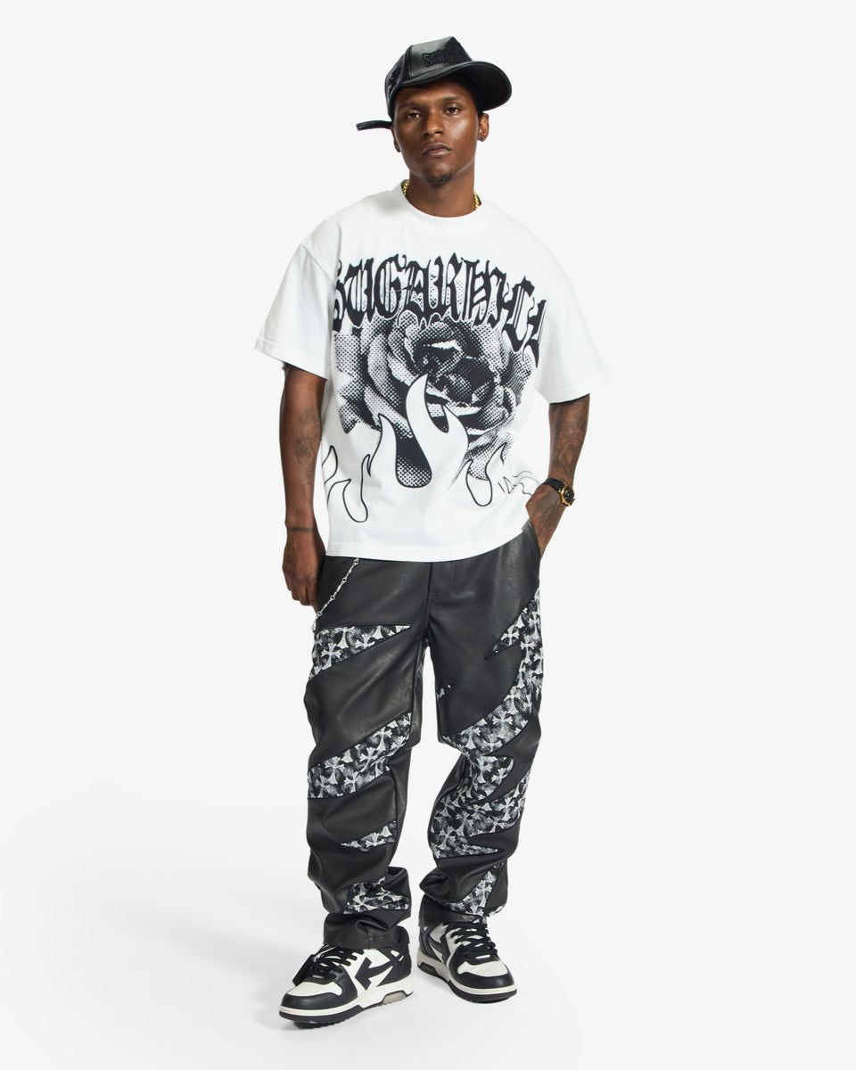 Person wearing a white graphic t-shirt, black cap, and patterned pants on a white background