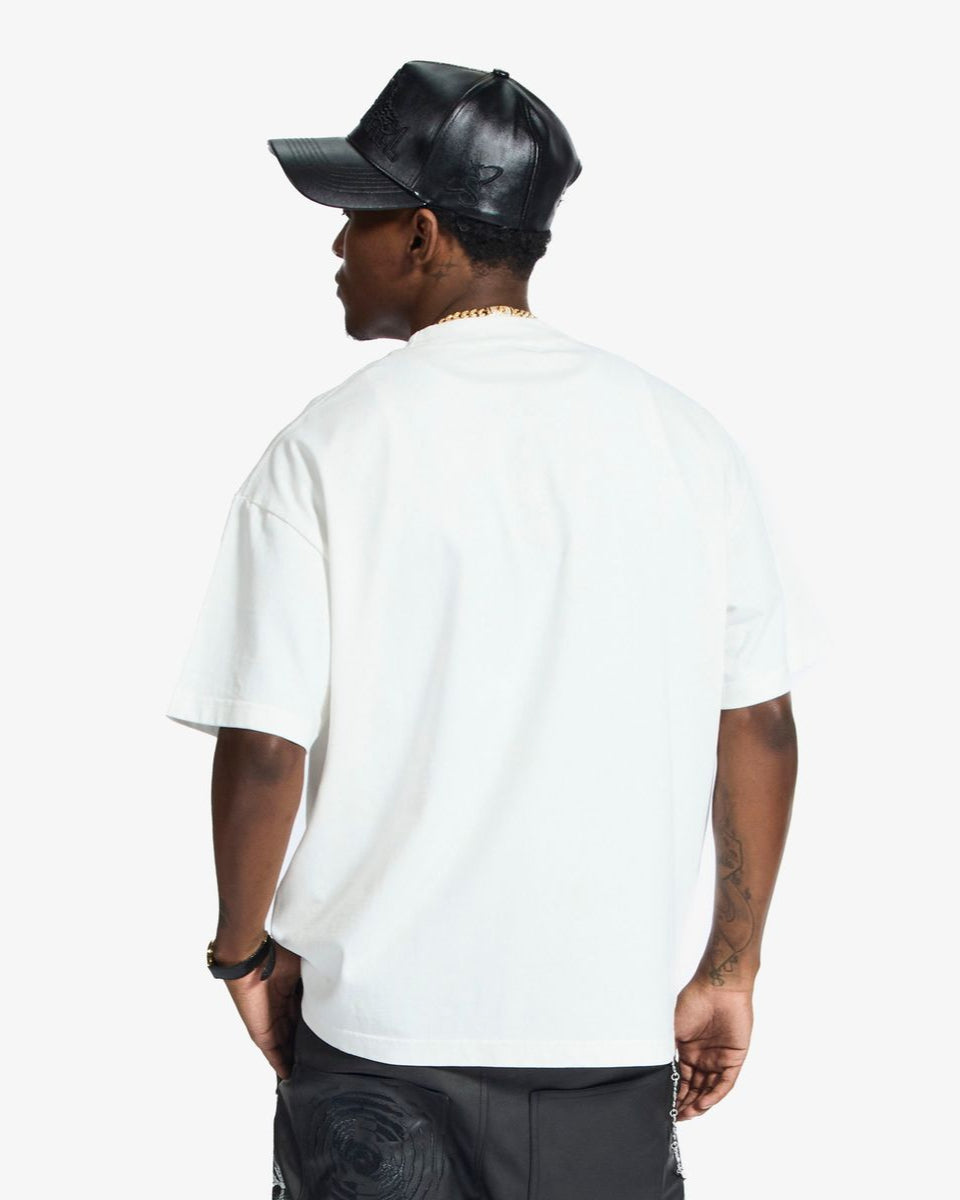 Person wearing a white t-shirt and black cap on a plain background