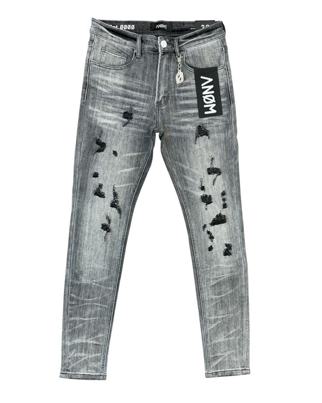 Distressed gray denim jeans with black ripped details, featuring a black hangtag with 'ANOM' on the pocket and a black inner waistband.