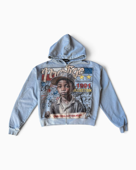 A light blue zip-up hoodie featuring a large graphic print on the front with a portrait of a young boy and text including 'Majestic' and '1991 Collection', shown against a plain light background.