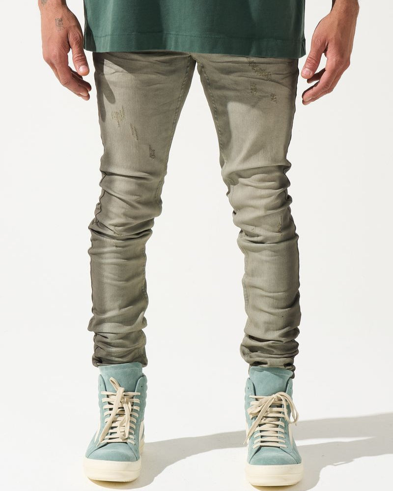 Person wearing green shirt, gray pants, and light blue sneakers on a white background