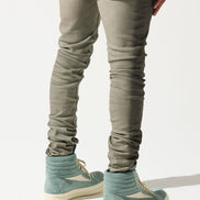 Person wearing beige pants and green shoes on a white background